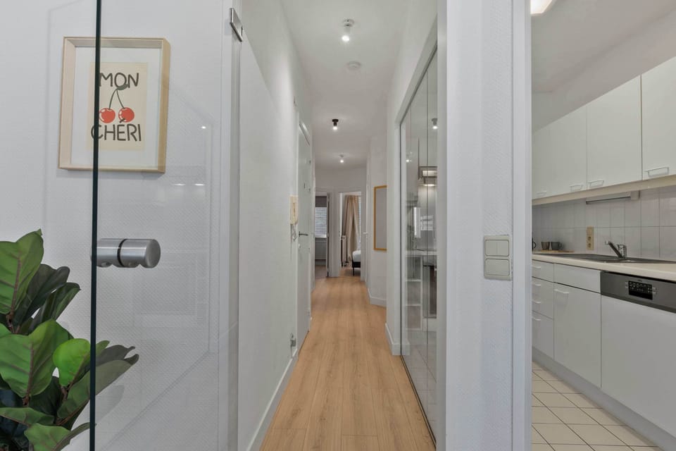 Light-filled hallway with wood flooring and greenery, welcoming you into this clean, contemporary holiday apartment in the heart of Knokke.