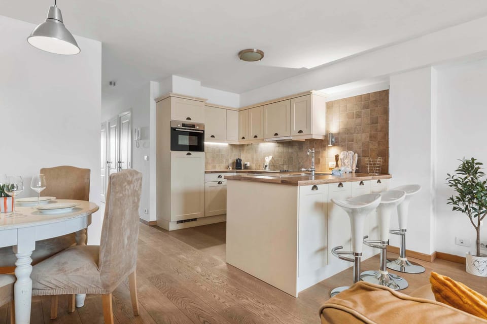 Open-plan kitchen and dining with sleek table and breakfast bar stools, perfect for sharing meals in Knokke.