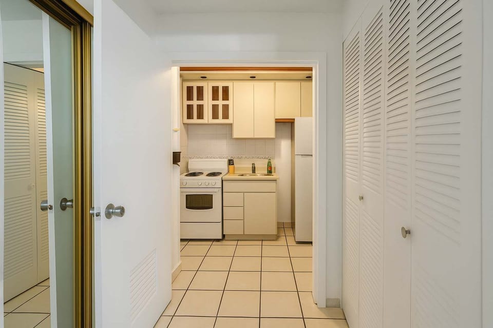 Bright entry hallway leading into the kitchenette, featuring mirrored closets and clean tile flooring. A practical layout that keeps the space organized and easy to navigate during your stay.