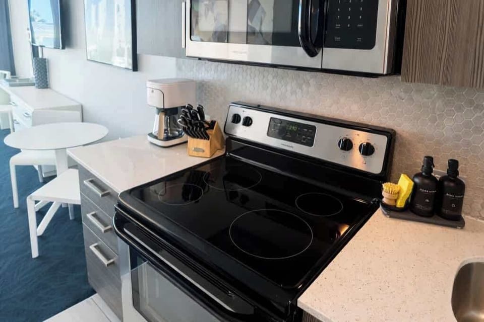 Close-up of the modern kitchenette highlighting the stove, microwave, coffee maker, and cooking essentials available for guests.