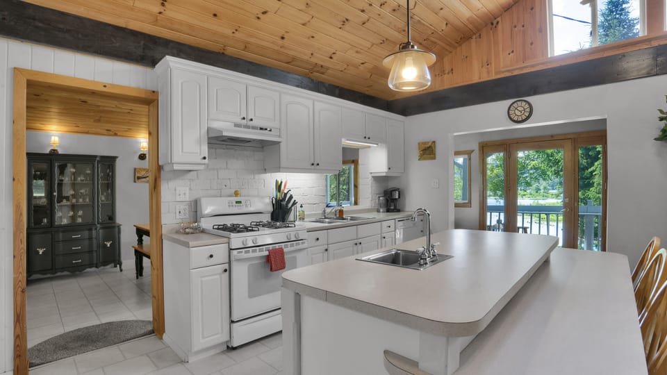 Spacious farmhouse-style kitchen featuring a marble island, white finishes, and warm natural wood details.
