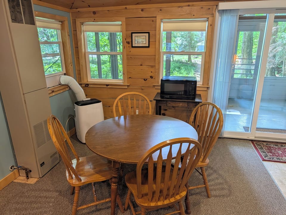 LIVING ROOM: The cute dining table in the living room with a window A/C unit and a microwave in the back