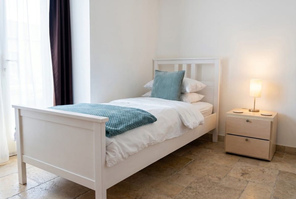 Bright single bedroom with soft lamplight, perfect for a restful retreat.