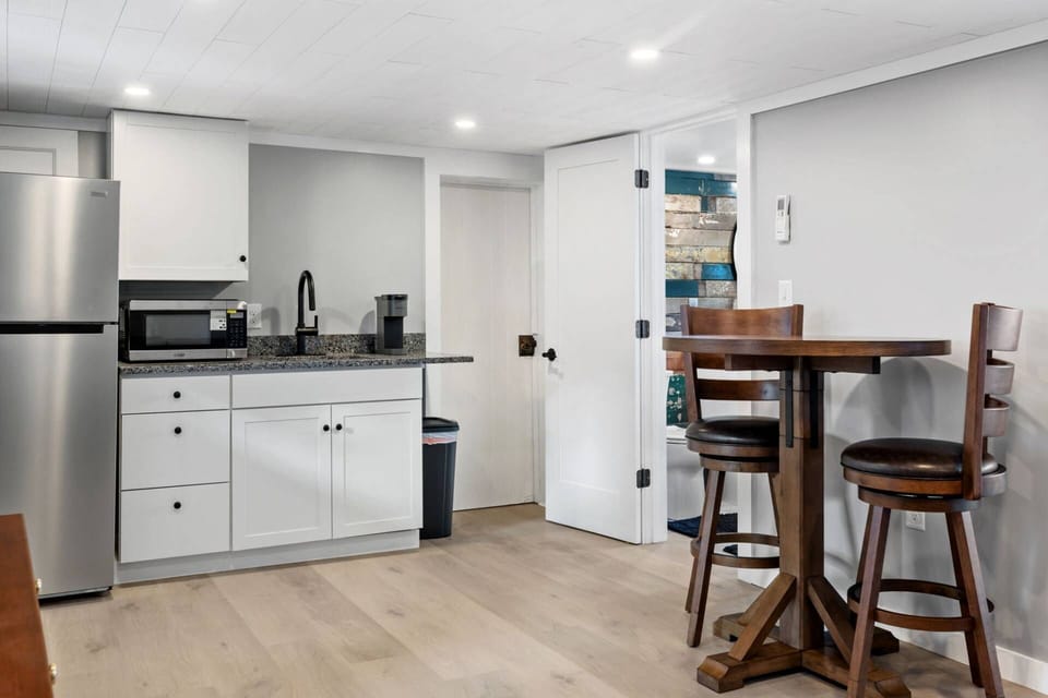 Kitchenette with fridge, microwave, Keurig, granite countertop, and high-top dining table for two.