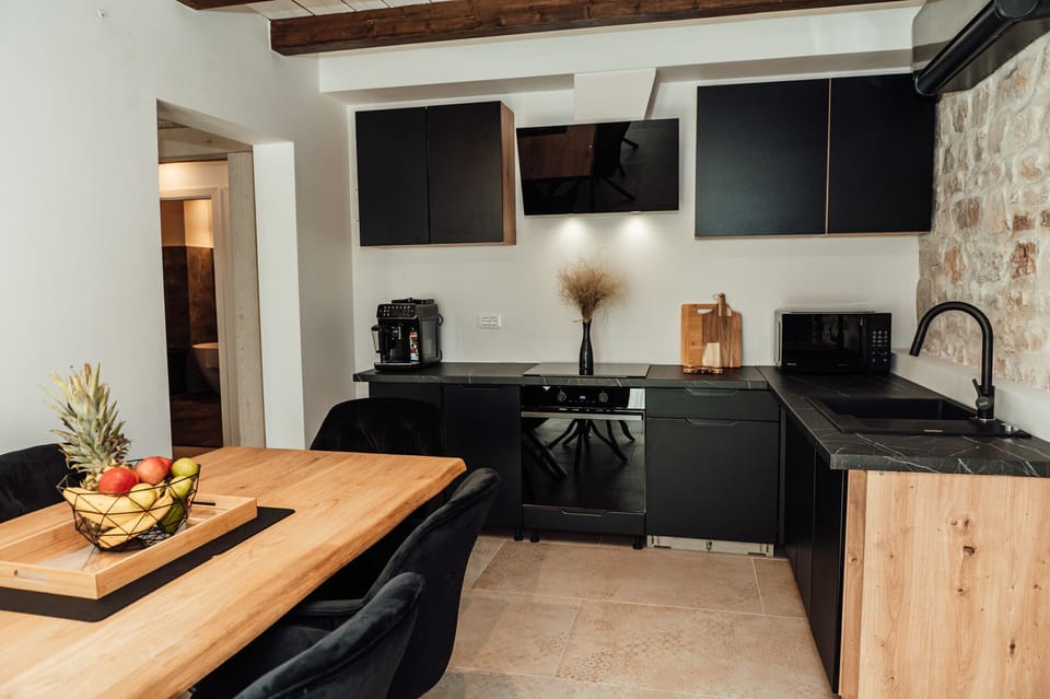 Separate fully equipped kitchen with dining area, modern appliances and stylish stone wall.