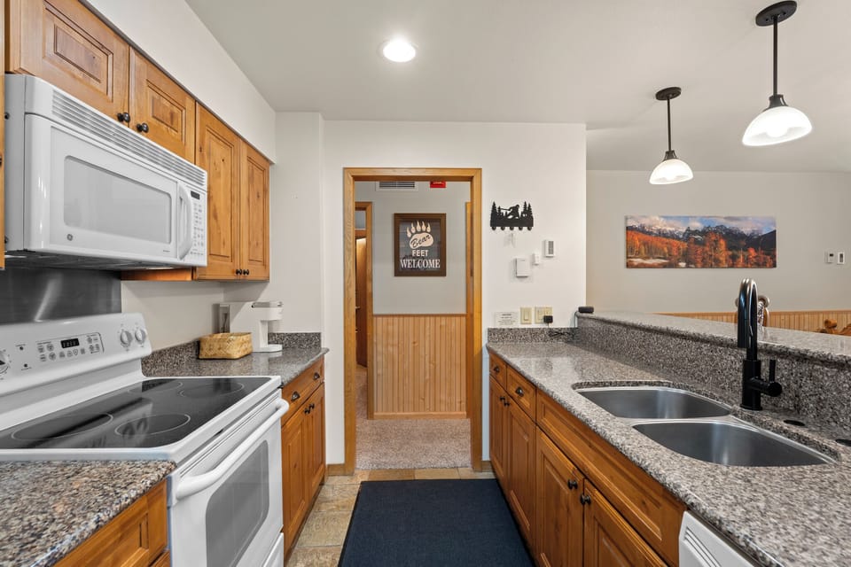 Your fully equipped kitchen awaits with granite counters, modern appliances, and warm wood cabinetry—perfect for preparing your favorite meals after a day of mountain adventures.