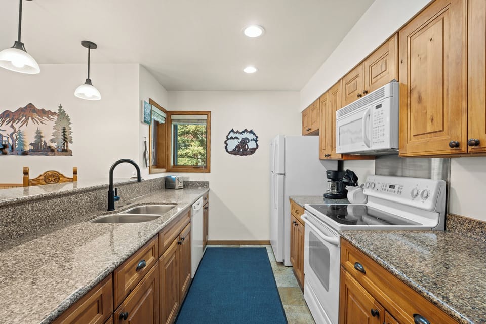 Cook up your favorite meals in this fully equipped kitchen featuring granite countertops, warm wood cabinetry, and all the appliances you need for a comfortable mountain getaway.