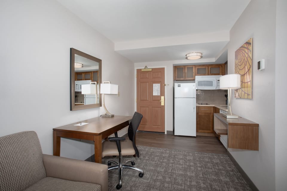 Studio with full kitchen, desk, seating, refrigerator, and microwave.