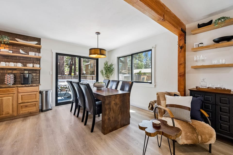 Sliding glass doors open to a backyard patio from the dining area with light wood floors and black-framed windows.