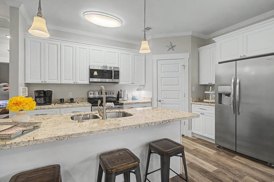 White cabinetry, granite countertops, and stainless steel appliances in the full kitchen with pendant lighting