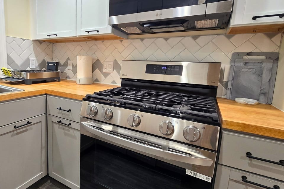 Modern kitchen with gas range, butcher-block counters, and chic tile backsplash
