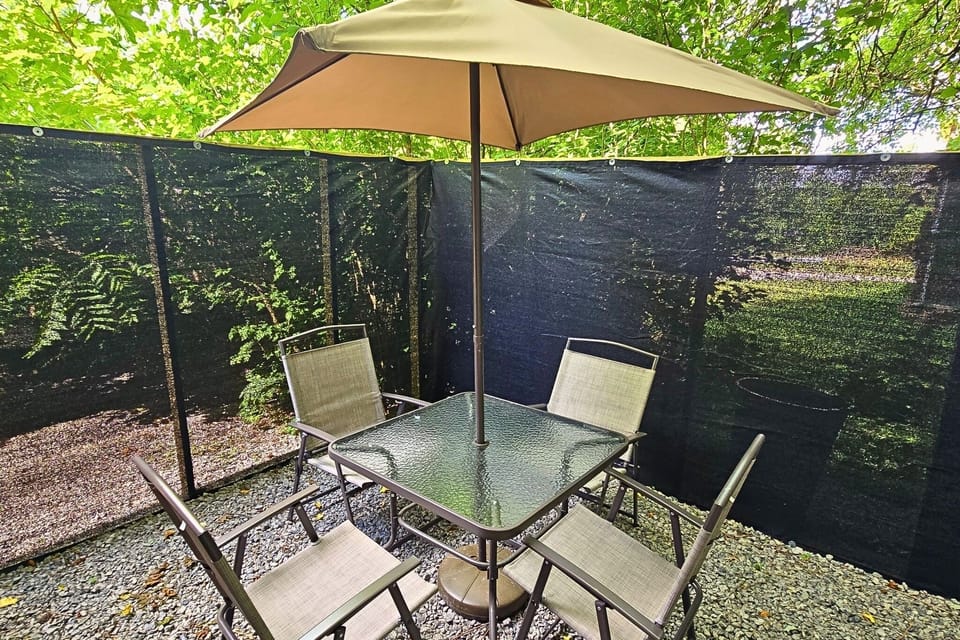 Private shaded patio with umbrella dining in a peaceful wooded setting