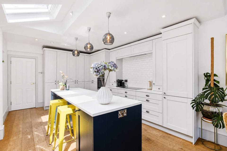 Kitchen: Crisp white cabinetry meets a chic navy island - your culinary adventure awaits!
