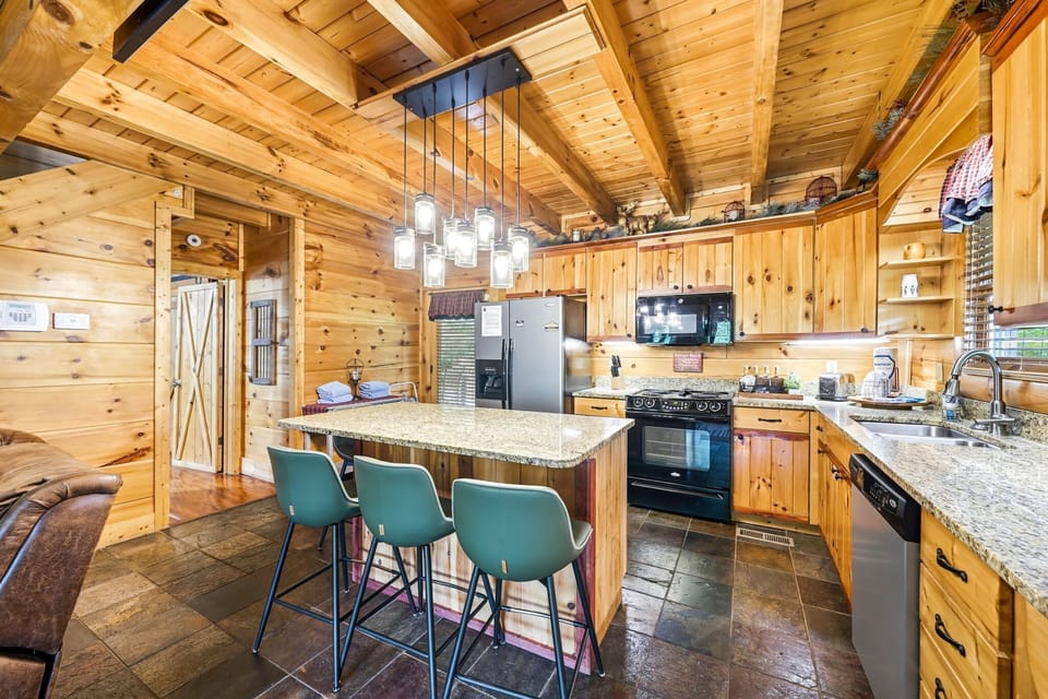 A fully equipped kitchen featuring sleek granite countertops, stainless steel appliances, and breakfast bar seating for 4.