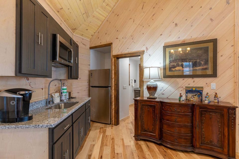The second Great Room features a charming wood-lined kitchenette with sleek granite counters, warm cabin character, and a convenient half bath — a beautifully appointed bonus space that adds function and style to the entire level.