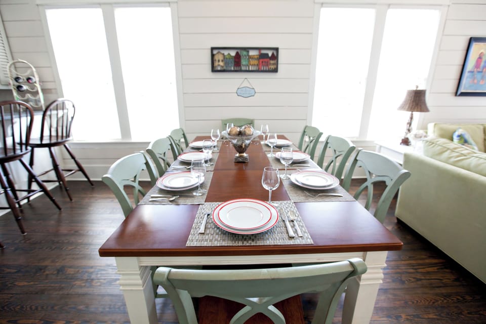 Gather around this inviting dining table, where natural light streams through tall windows as you enjoy meals with loved ones in a bright, cheerful space designed for togetherness.