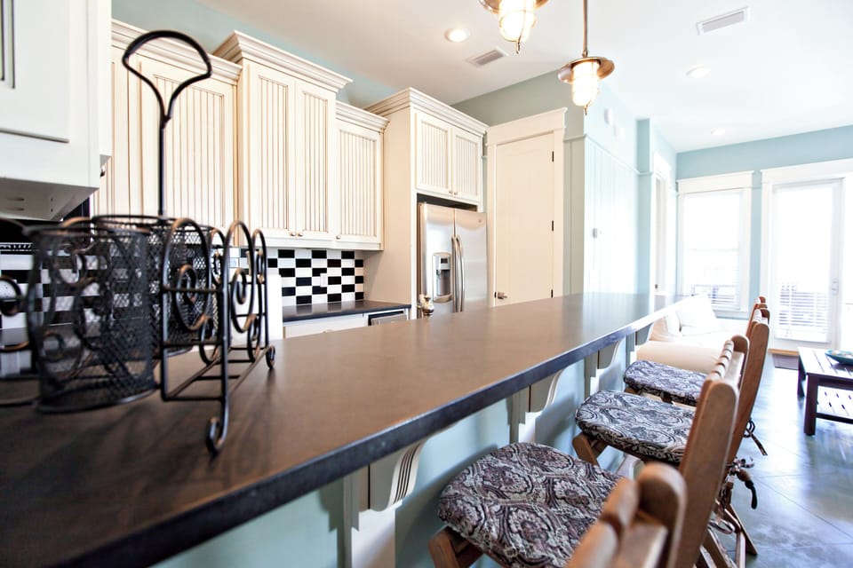 Gather around the spacious breakfast bar for morning coffee or casual meals in this fully equipped kitchen with stainless steel appliances and classic white cabinetry.