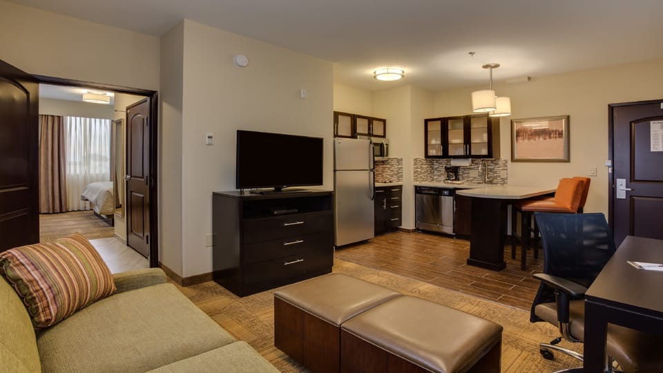 Open-plan living area and fully equipped kitchenette with refrigerator, sofa, and flat-screen TV.
