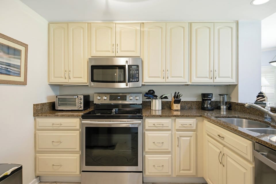 Creamy cabinetry and speckled granite counters create a bright, functional kitchen space. Elegant stainless steel appliances pair with a tidy array of culinary tools, making home-cooked meals a delightful part of your stay.