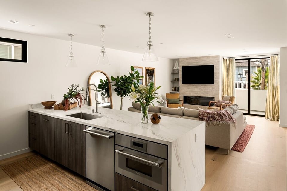 The open-concept kitchen is designed for everyday living and entertaining, featuring a waterfall island with bar seating, quartz countertops, and stainless steel appliances, with a seamless connection to the living space.