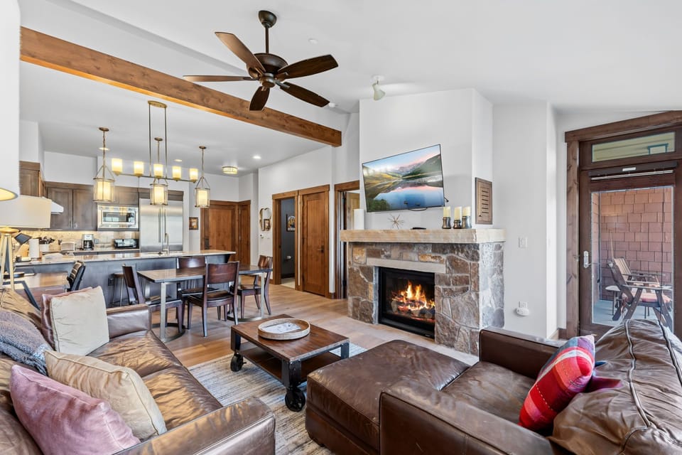 Gather around your stone fireplace in this open-concept mountain retreat. The spacious living area flows into a dining space and fully-equipped kitchen, complete with exposed beams overhead and a cozy balcony just steps away.