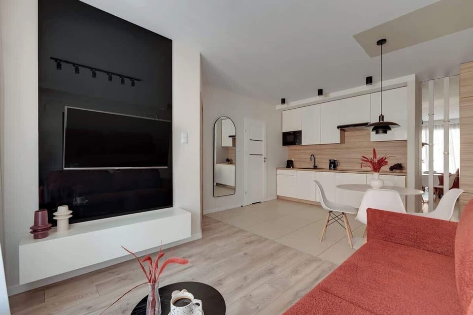 Wygodna, wyrazista rozkładana sofa z funkcją spania znajduje się naprzeciwko dużego telewizora z dostępem do funkcji Smart TV.