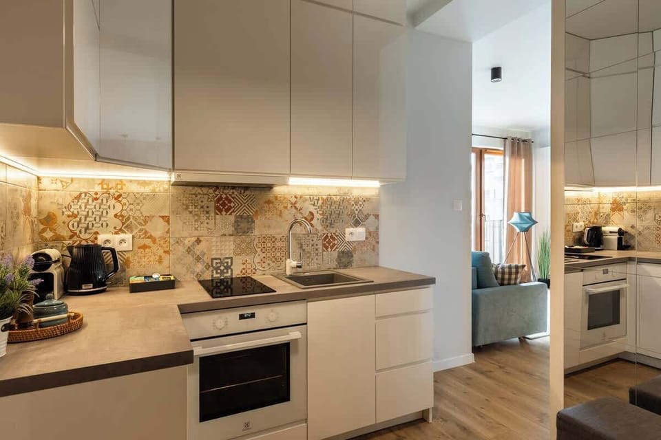 Funkcjonalny aneks kuchenny został w pełni wyposażony w piekarnik, zmywarkę, płytę kuchenną, czajnik oraz ekspres do kawy.