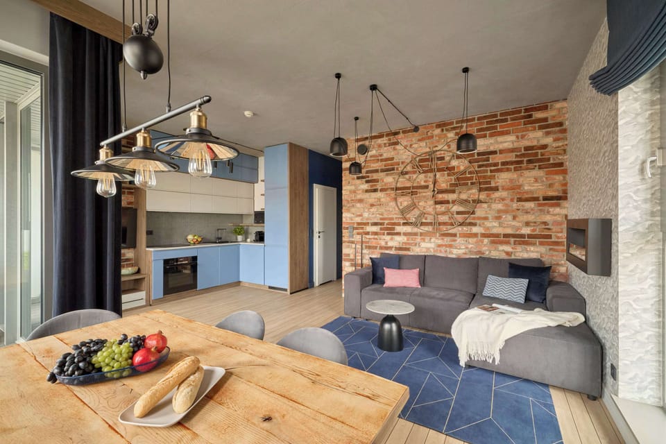 Centralną częścią apartamentu jest salon połączony z aneksem kuchennym. W salonie znajduje się rozkładana sofa z funkcją spania oraz telewizor z dostępem do kanałów kablowych i funkcji Smart TV.