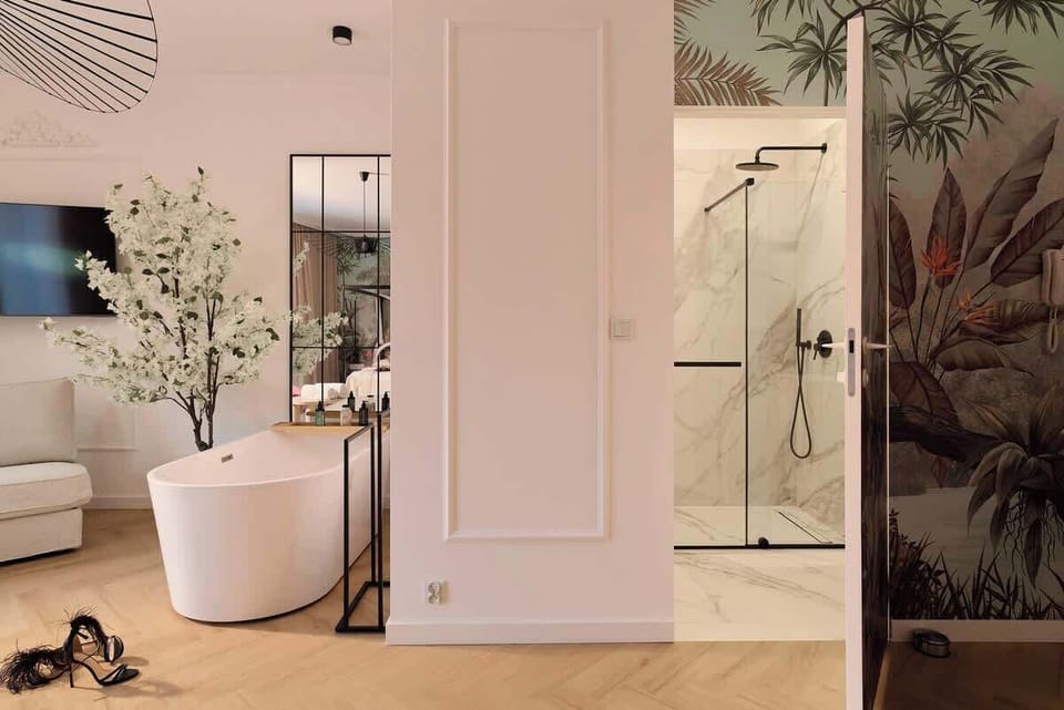 Nowoczesna łazienka z przestronnym prysznicem, utrzymana w jasnej, eleganckiej stylistyce. Całość tworzy spójną, stylową przestrzeń, idealną na komfortowy pobyt we dwoje lub wyjątkowy city break.