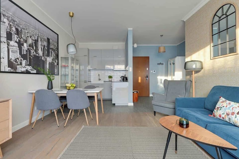 Przytulny salon to jasna, funkcjonalna przestrzeń idealna do relaksu. Znajduje się tu wygodna, rozkładana sofa stanowiąca dodatkowe miejsce do spania oraz fotel tworzący komfortowy kącik wypoczynkowy. Naprzeciw stoi telewizor z dostępem do kanałów TV