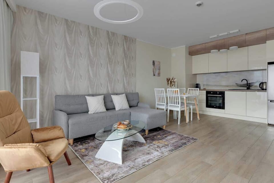 W salonie znajduje się rozkładana sofa zapewniająca dodatkowe spanie, a jasne wnętrze z designerskimi akcentami i dużymi oknami tworzy przytulny, nowoczesny klimat.