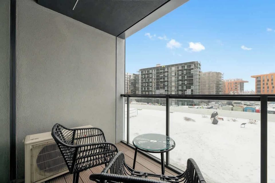 Prywatny balkon z zestawem mebli wypoczynkowych, idealny na poranną kawę lub chwilę relaksu. Przeszklona balustrada zapewnia przestrzeń, widok i dużo naturalnego światła.