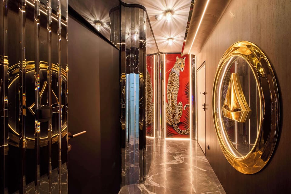 Apartament łączy luksusowy styl glamour, elementy art déco, głębokie kolory, złote detale, lustrzane powierzchnie oraz spektakularne oświetlenie. Każda część wnętrza została dopracowana tak, aby tworzyć spójną, elegancką i nastrojową przestrzeń.