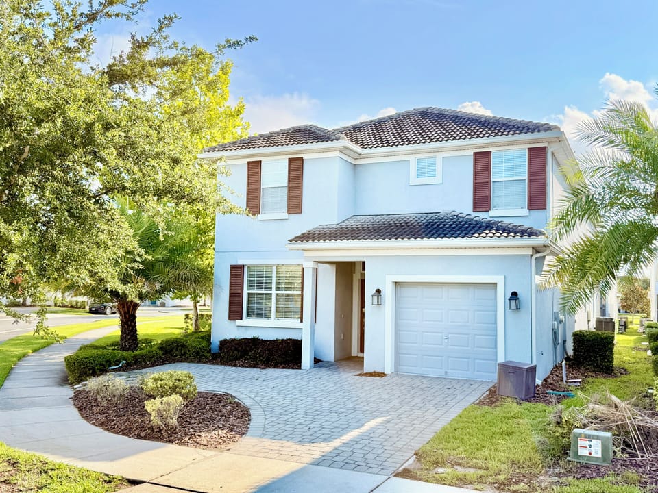 Beautiful two-story resort vacation home with palm trees and paved driveway.