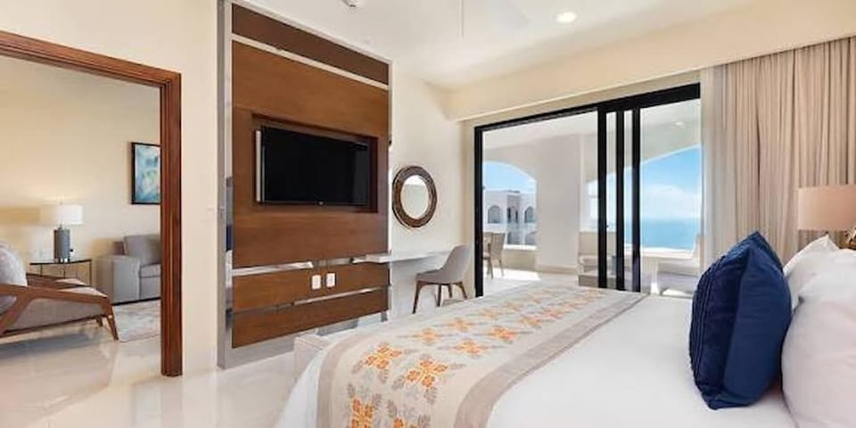 Elegant primary suite featuring a king bed, smart TV, and private balcony access
