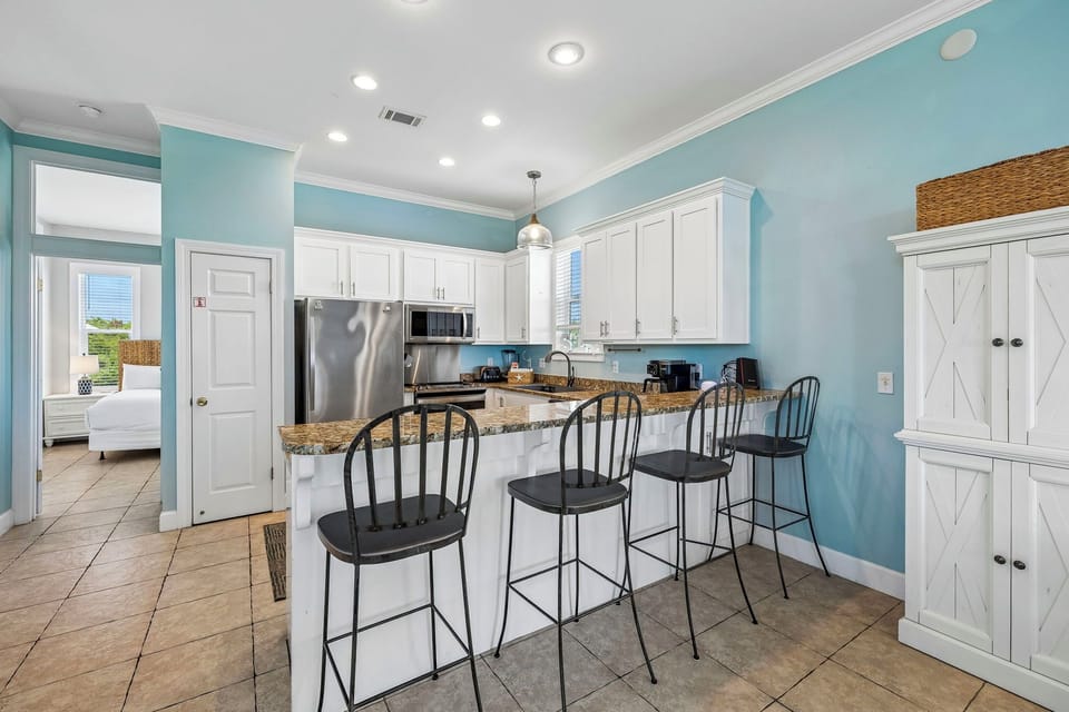 Gather around the island for your morning coffee in this bright, coastal-inspired kitchen. White cabinetry, granite countertops, and stainless steel appliances make meal prep effortless.