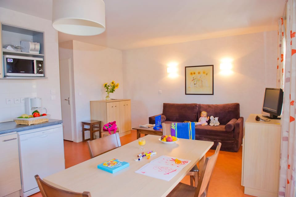 Open-plan living and dining area with a sofa bed, four-seat dining table, microwave, and coffee maker within reach.