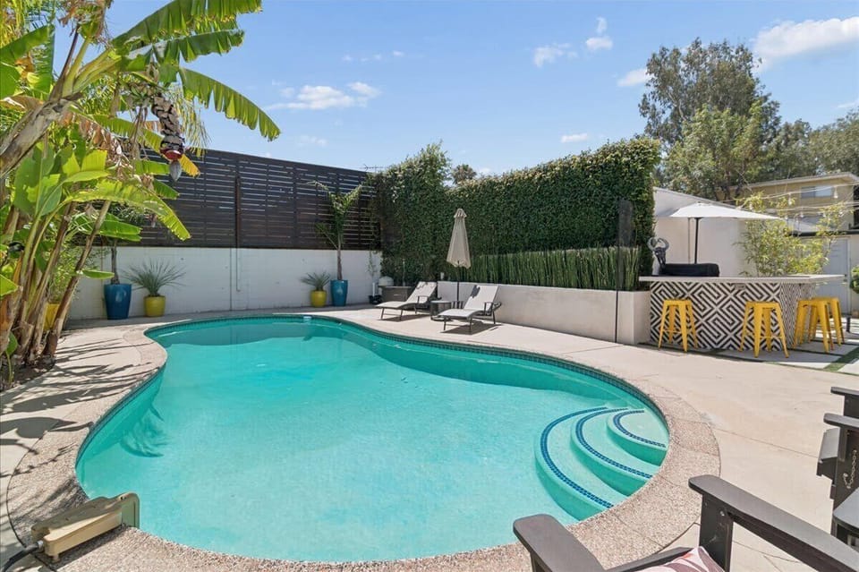Sparkling private swimming pool with multiple seating areas and tropical foliage, adding to the beautiful ambiance