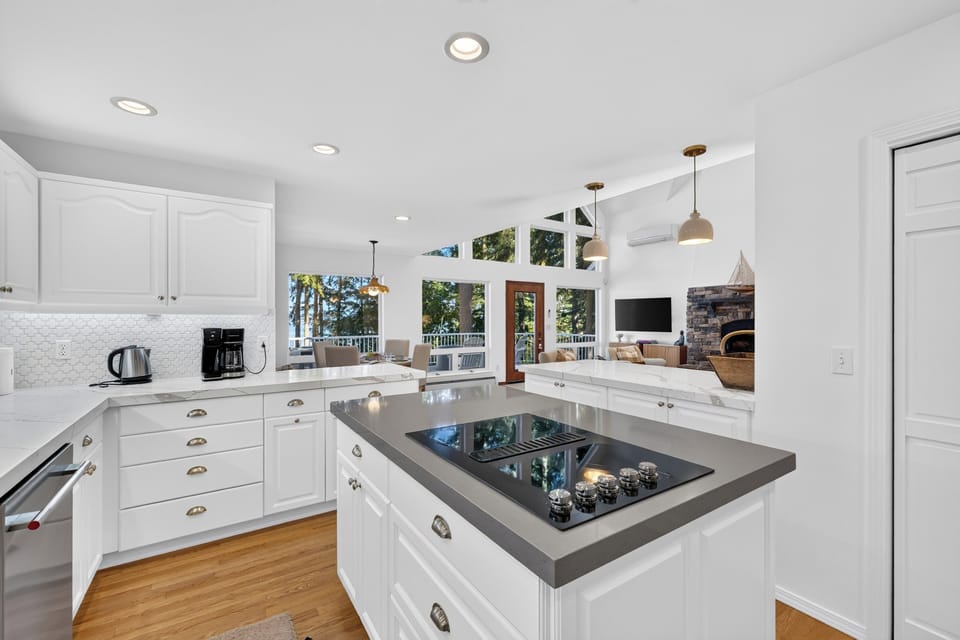 Gourmet kitchen with clean white cabinetry and an expansive central island featuring an integrated cooktop.
