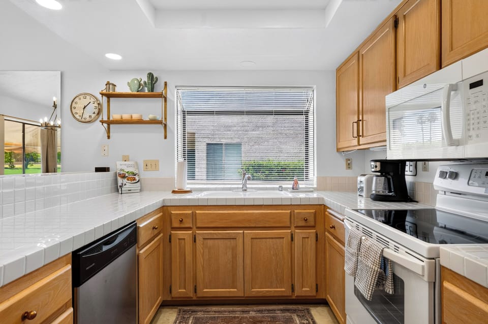 Highly functional kitchen featuring classic wood cabinetry, modern appliances, and a window that keeps the space bright.