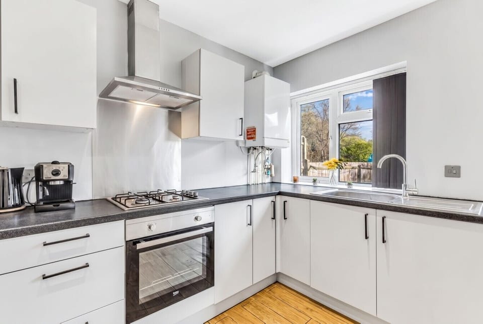 Sleek white kitchen with gas hob and garden view window