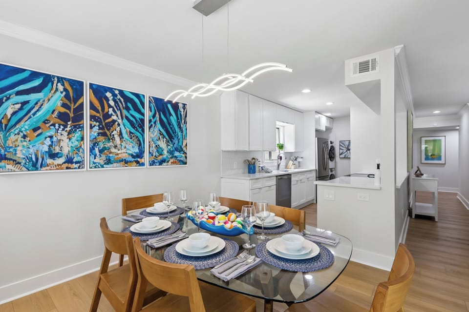 Gather around this stylish dining table, where modern design meets warm hospitality. The open layout invites you to enjoy meals while chatting with loved ones in the sleek, fully-equipped kitchen nearby.
