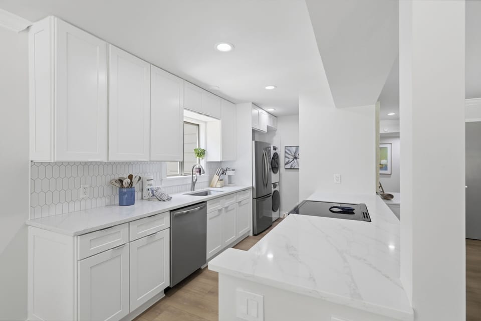 Your pristine kitchen awaits with gleaming marble countertops, crisp white cabinetry, and all the modern appliances you need for easy meal prep during your stay.