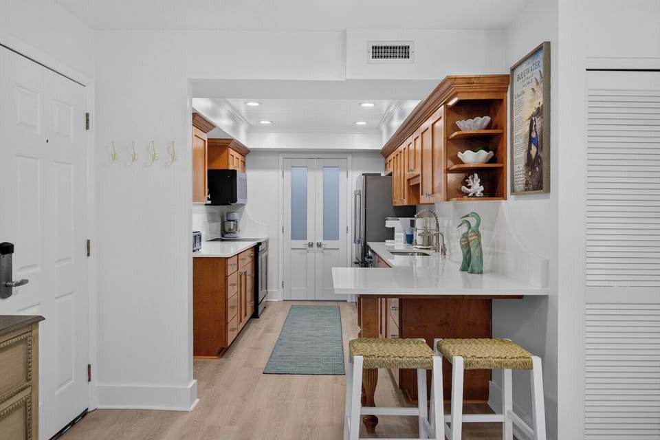 Step into your fully equipped kitchen with warm wood cabinetry, modern appliances, and a breakfast bar—perfect for cooking meals and sipping morning coffee.