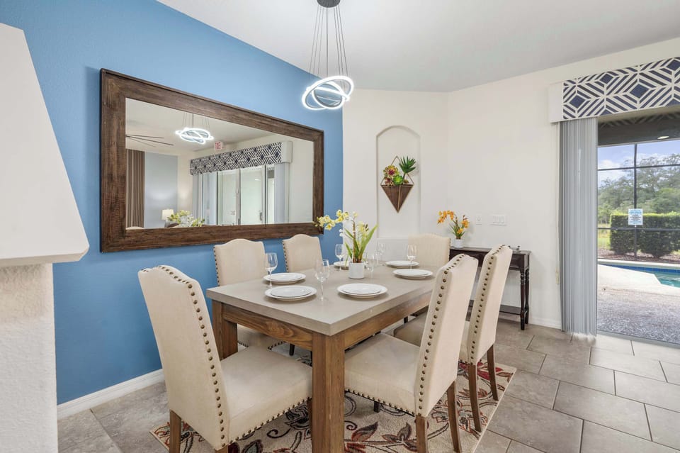 Dining area with a large mirror and sliding doors opening to a pool view.