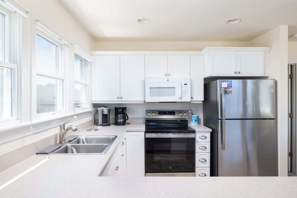 Fully Equipped Kitchen with Refrigerator, Range and Oven, Microwave, Dishwasher, Dual Coffee Makers, Ample Counter Space, and a Breakfast Bar with Seating, Perfect for Preparing Meals and Gathering with Family and Friends