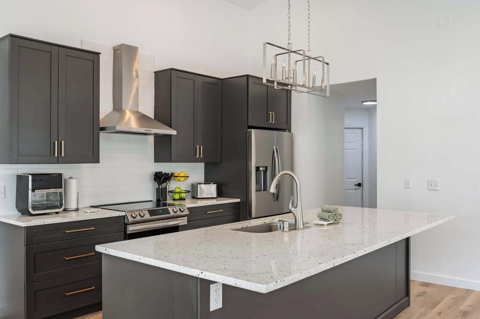 Modern kitchen with dark cabinetry and a large quartz island for meal preparation.