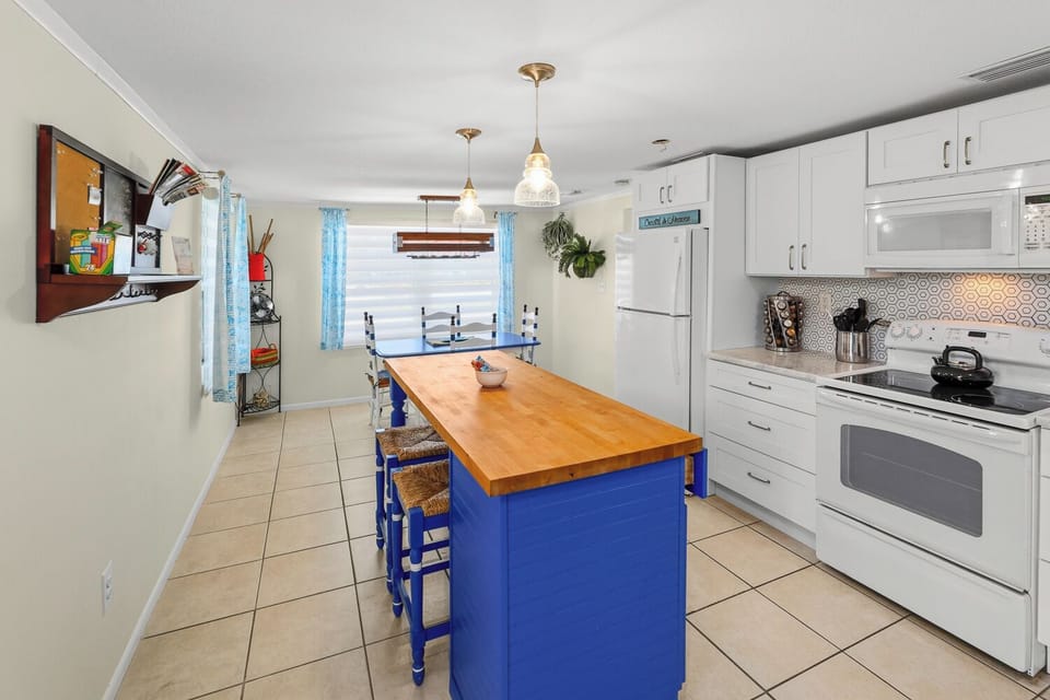 Bright kitchen with large island, dining space, and cheerful coastal accents