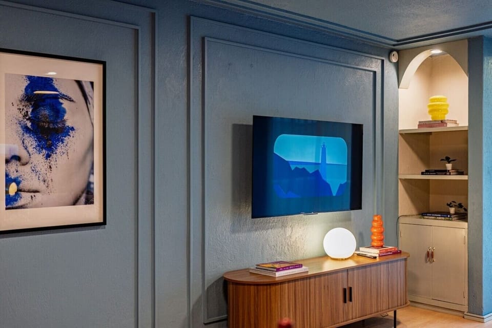 Relax in the living area with a Smart TV, soft lighting, and stylish blue wall details.