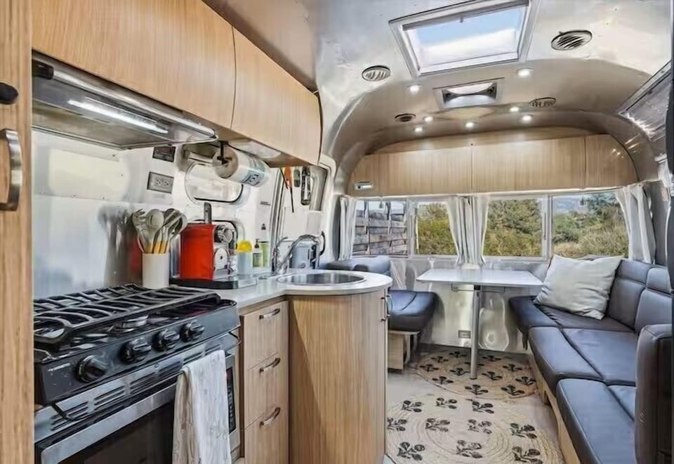 Bright Airstream interior with full kitchen, dinette, and cozy lounge seating